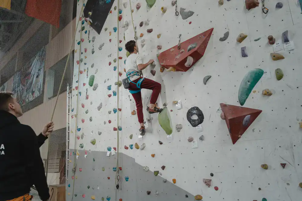 Climbing coach demonstrating a technique on the bouldering wall